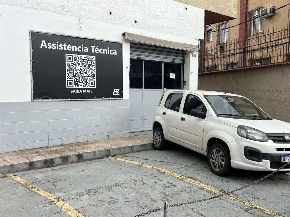 Carro branco estacionado em frente à entrada de uma assistência técnica