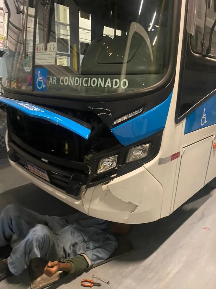 Mecânico deitado sob a frente de um ônibus na garagem
